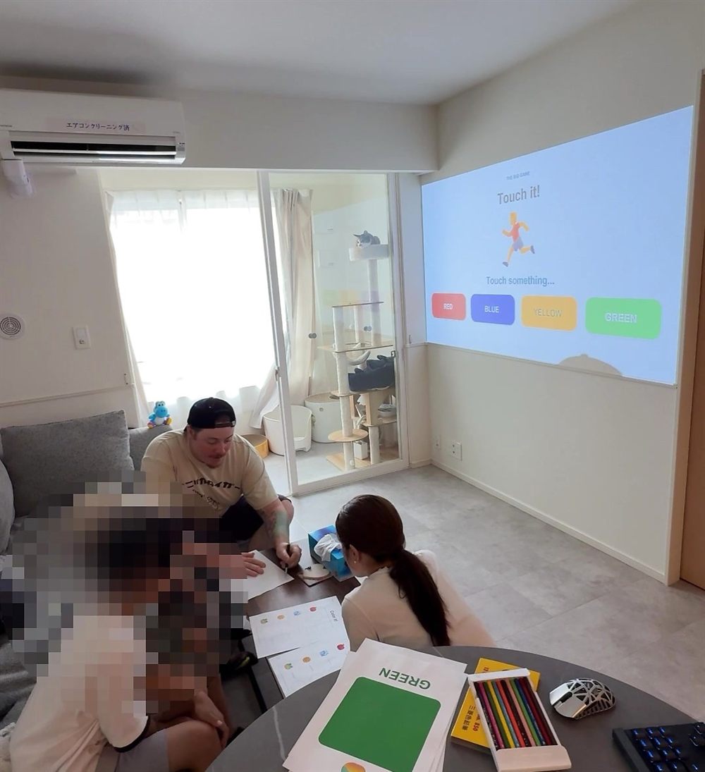 ご自宅でのレッスンの様子。プロジェクターに映した色のスライドを使って、親子で英語を学んでいます。